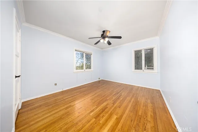 a view of empty room with wooden floor and fan