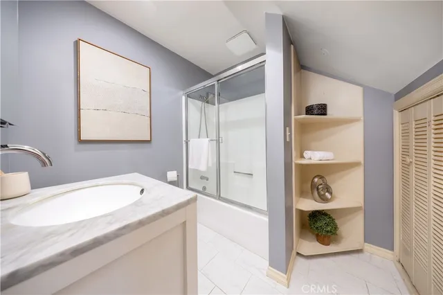 a bathroom with a granite countertop sink a mirror and shower
