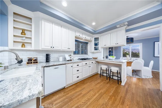 a kitchen with white cabinets and wooden floor