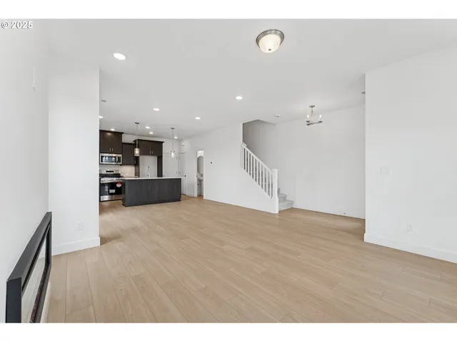 a view of kitchen and empty room with wooden floor