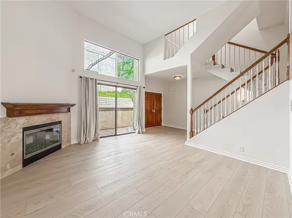 a view of an empty room with wooden floor fireplace and a window