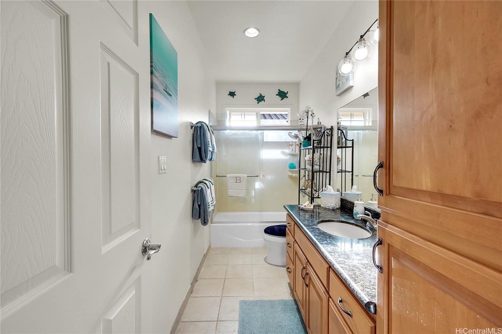92-1306 Hauone Street Kapolei, HI 96707 - Photo 17 of 25 a bathroom with a granite countertop sink a mirror and shower