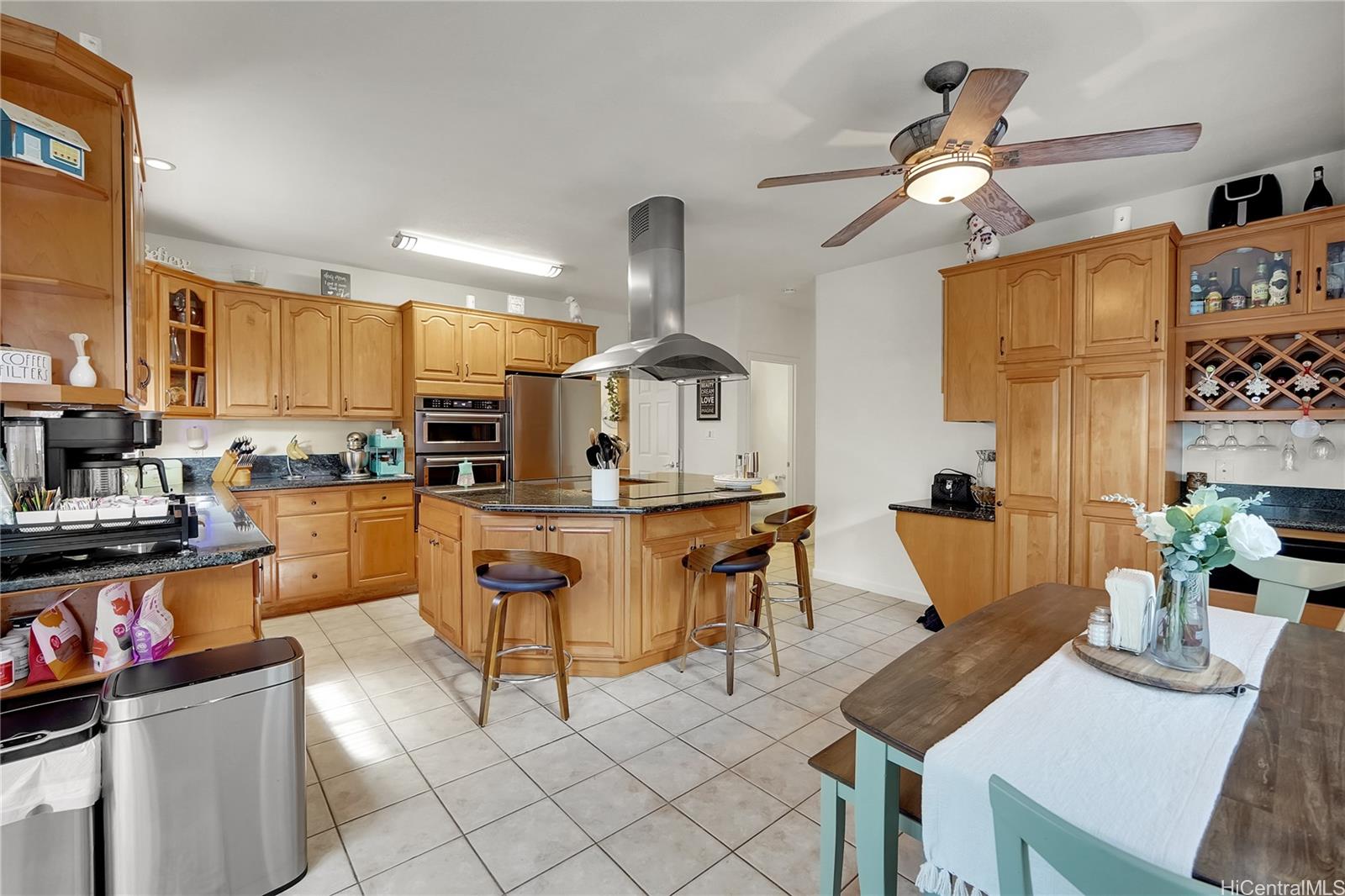92-1306 Hauone Street Kapolei, HI 96707 - Photo 8 of 25 a kitchen with stainless steel appliances kitchen island granite countertop a table chairs and a refrigerator