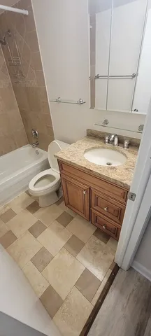 a bathroom with a granite countertop sink and a toilet