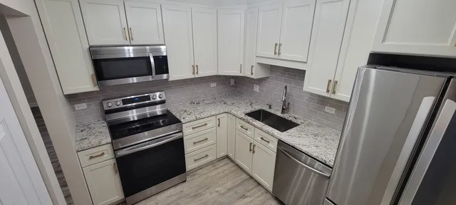 a kitchen with granite countertop white cabinets and stainless steel appliances