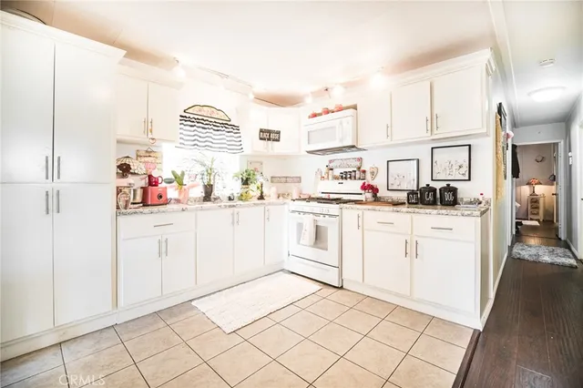 a kitchen with granite countertop white cabinets and white appliances