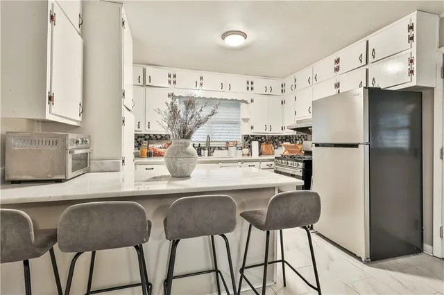 a kitchen with stainless steel appliances granite countertop a table chairs refrigerator and sink