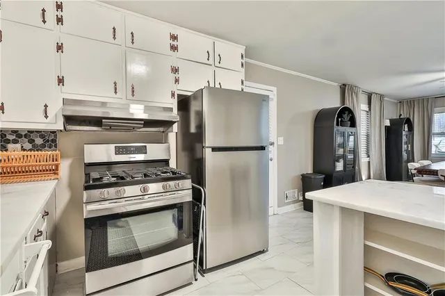 a kitchen with kitchen island a counter top space stainless steel appliances and cabinets