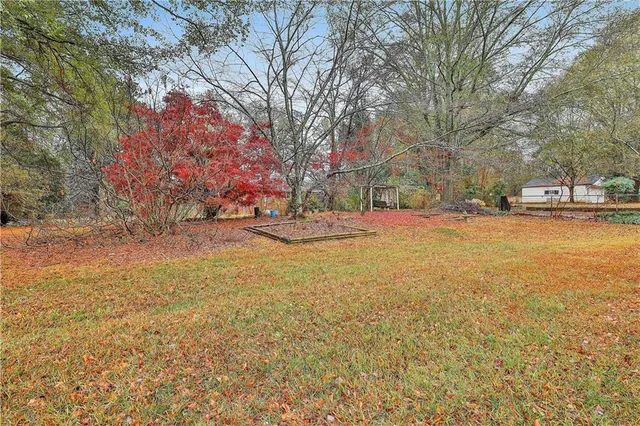 a view of a house with a yard and covered with trees