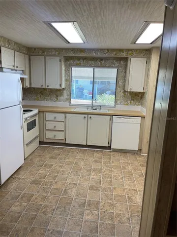 a kitchen with granite countertop a sink a stove top oven and cabinets