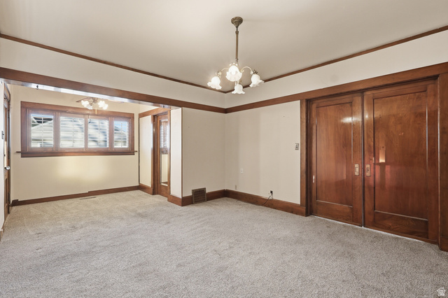 202 Main Street Smithfield, UT 84335 - Photo 10 of 32 Empty room with light colored carpet, a chandelier, and crown molding