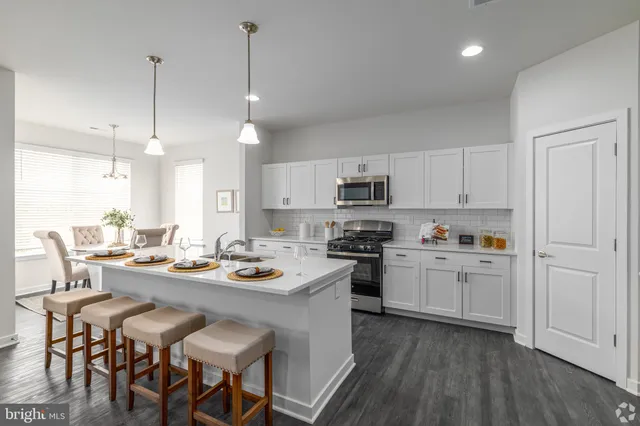 a kitchen with stainless steel appliances kitchen island granite countertop a stove a sink a dining table and chairs with wooden floor