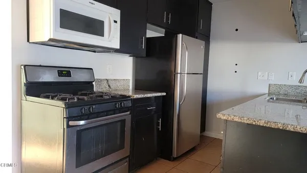 a kitchen with stainless steel appliances granite countertop a refrigerator stove and microwave