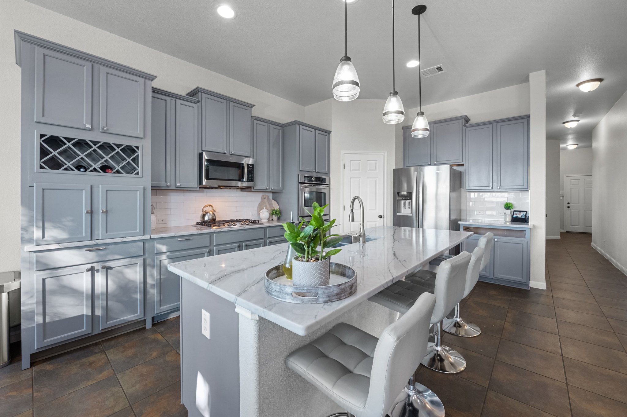 22112 Rock Wren Road Spicewood, TX 78669 - Photo 11 of 40 Kitchen featuring a kitchen breakfast bar, gray cabinets, hanging light fixtures, and a center island with sink
