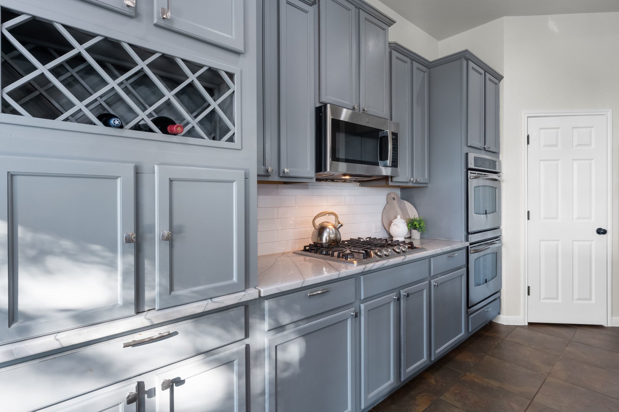22112 Rock Wren Road Spicewood, TX 78669 - Photo 12 of 40 Kitchen with stainless steel appliances, backsplash, light stone countertops, and gray cabinets