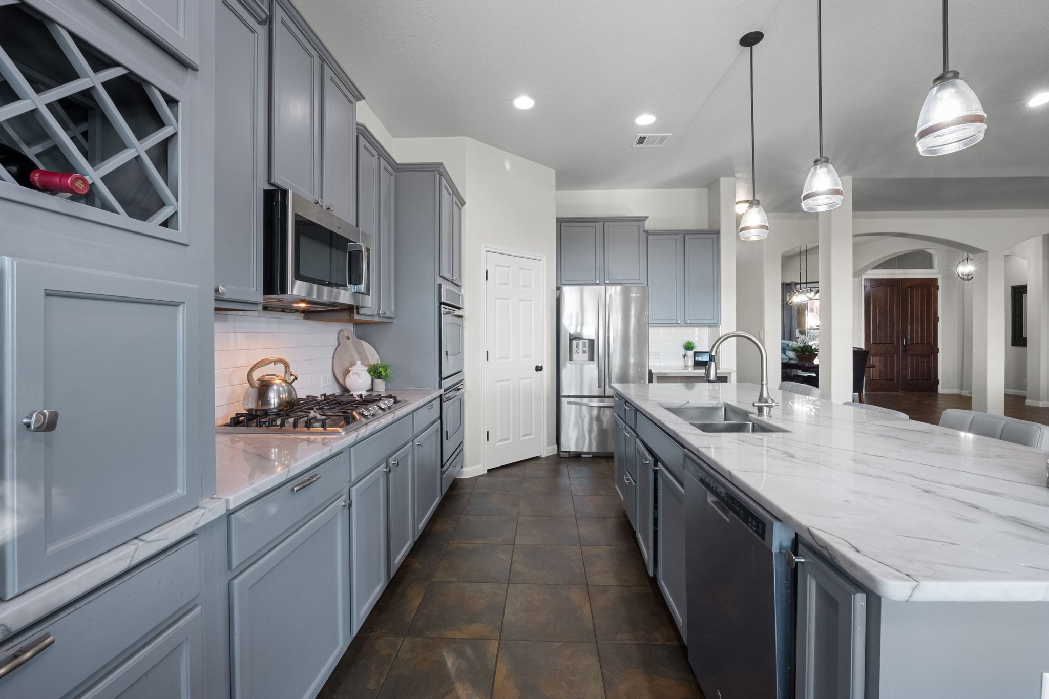 22112 Rock Wren Road Spicewood, TX 78669 - Photo 13 of 40 Kitchen featuring arched walkways, decorative light fixtures, stainless steel appliances, backsplash, and light stone counters