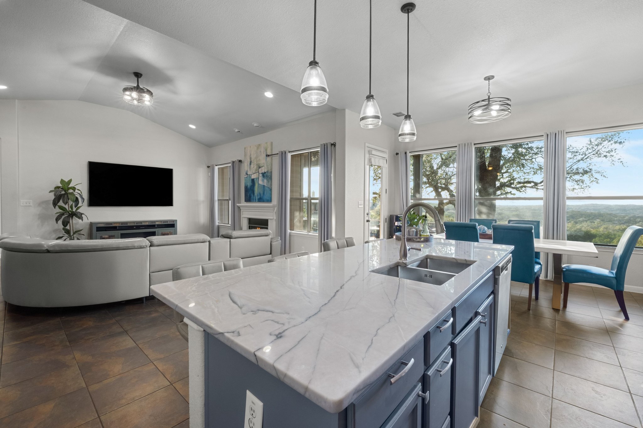 22112 Rock Wren Road Spicewood, TX 78669 - Photo 40 of 40 Kitchen featuring light stone counters, pendant lighting, lofted ceiling, open floor plan, and a kitchen island with sink