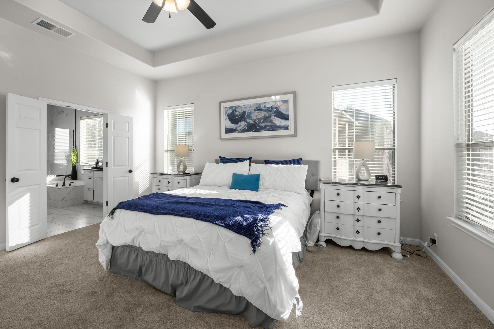 22112 Rock Wren Road Spicewood, TX 78669 - Photo 17 of 40 Bedroom with a raised ceiling, light colored carpet, connected bathroom, and a ceiling fan