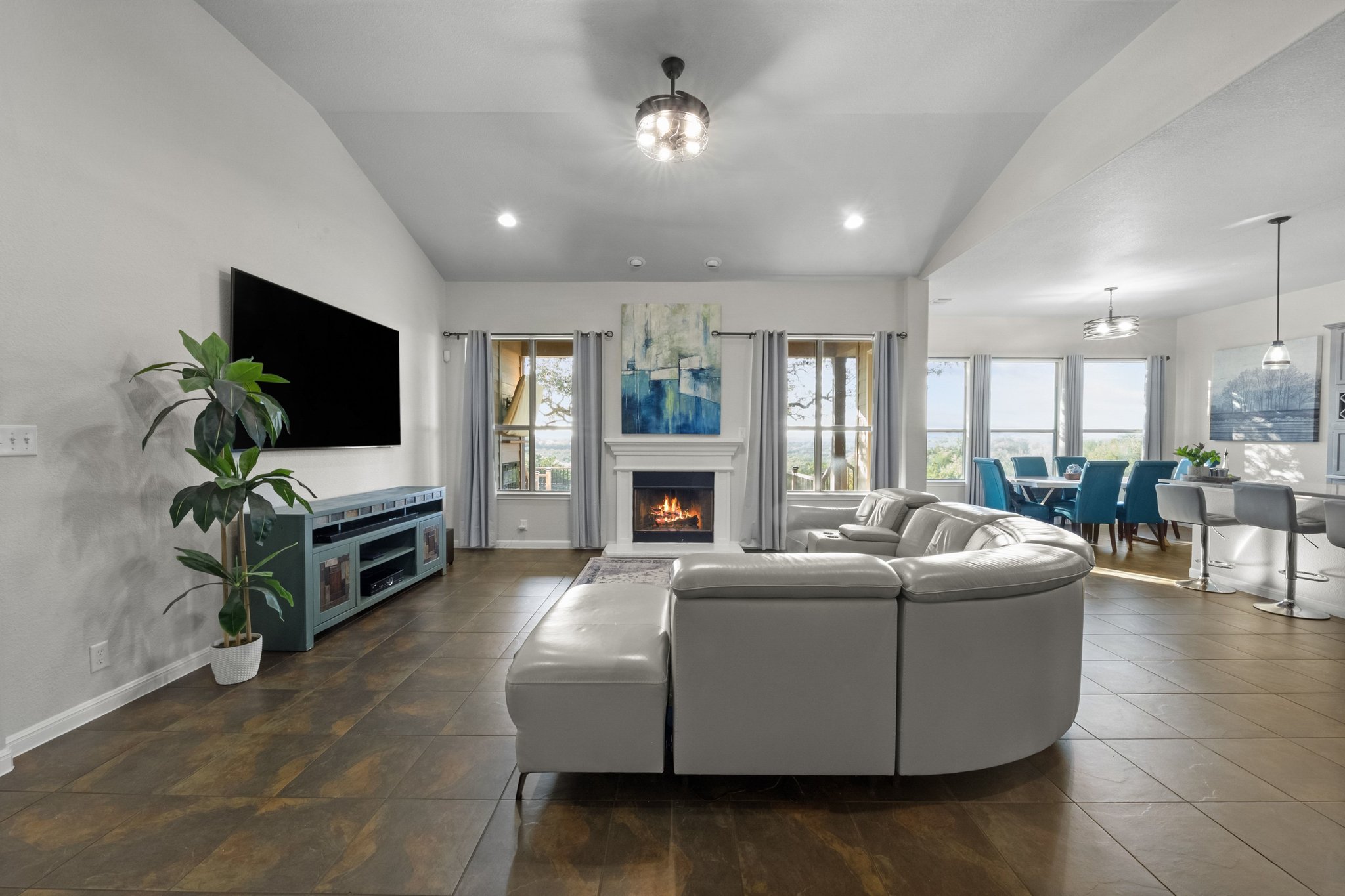 22112 Rock Wren Road Spicewood, TX 78669 - Photo 7 of 40 Living area featuring lofted ceiling, suspended lighting, and a lit fireplace