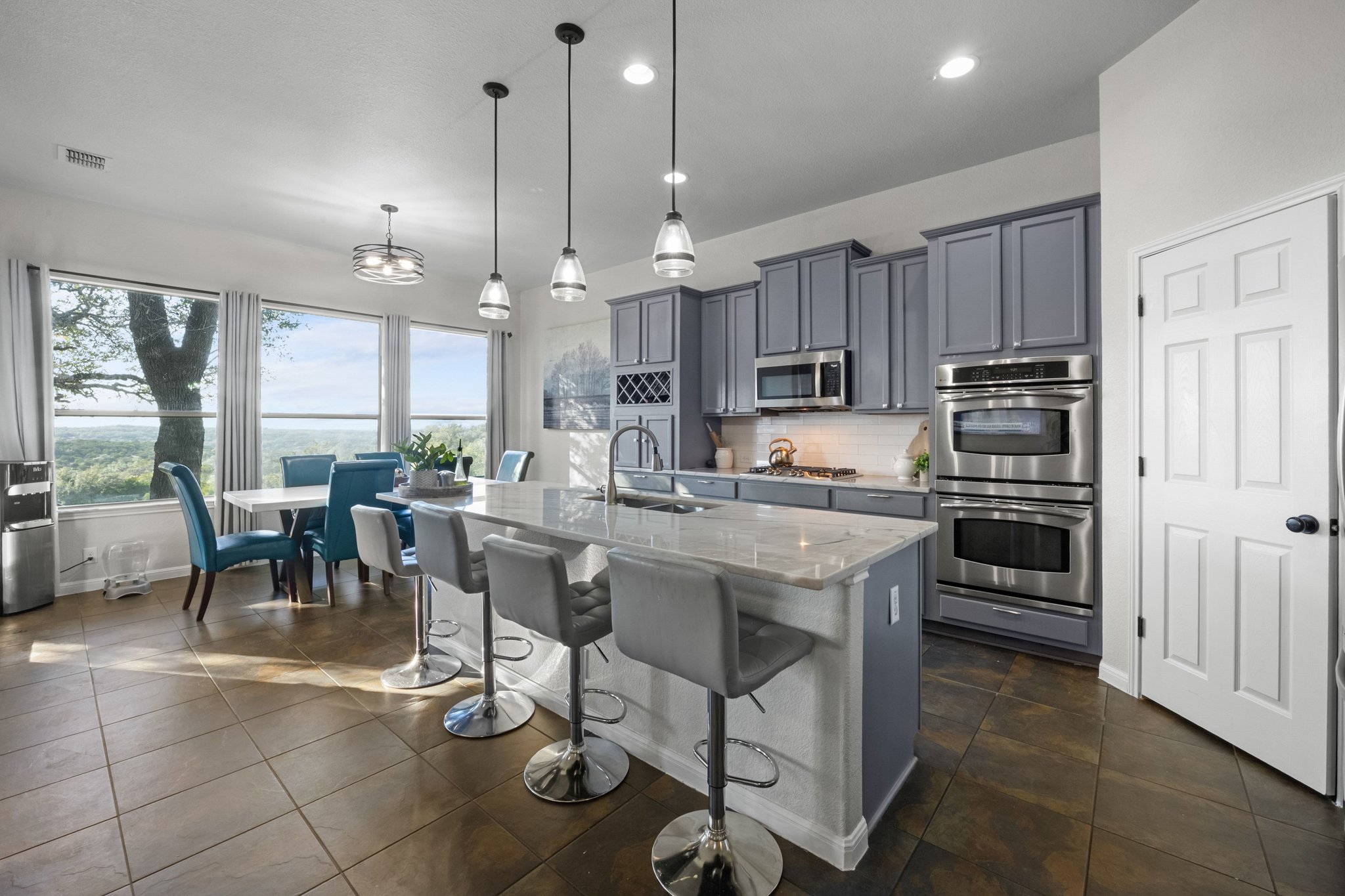 22112 Rock Wren Road Spicewood, TX 78669 - Photo 10 of 40 Kitchen featuring a breakfast bar area, gray cabinets, stainless steel appliances, and light stone counters