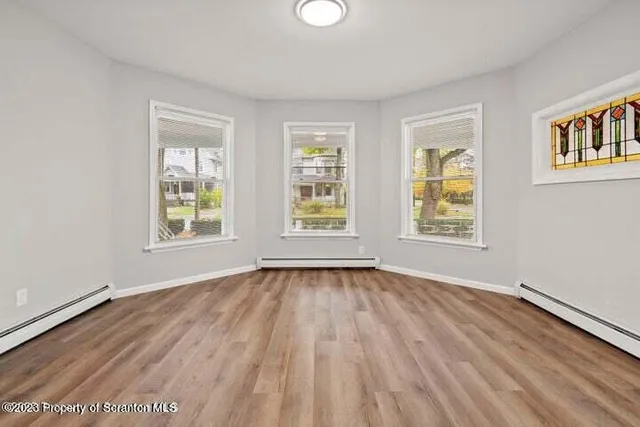 a view of an empty room with wooden floor and a window