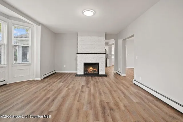 a view of empty room with wooden floor and fireplace