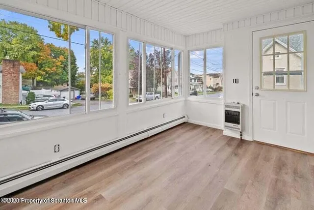 a view of an empty room with a window and wooden floor