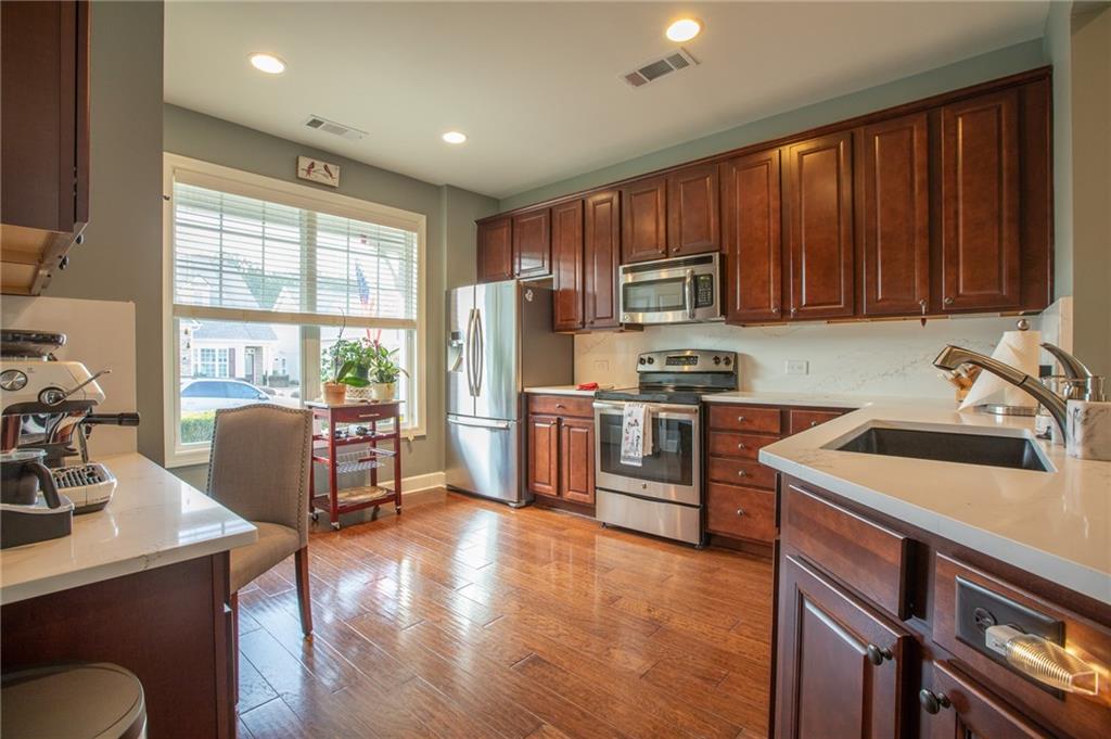 3538 Black Cherry Point Gainesville, GA 30504 - Photo 4 of 44 a kitchen with granite countertop wooden cabinets a stove a sink and a refrigerator