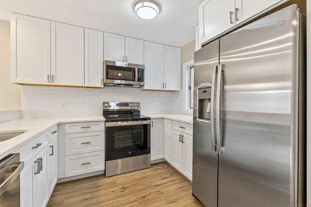 a kitchen with white cabinets stainless steel appliances and a refrigerator
