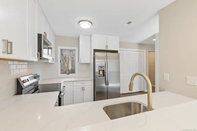 a kitchen with stainless steel appliances granite countertop a sink a stove and refrigerator