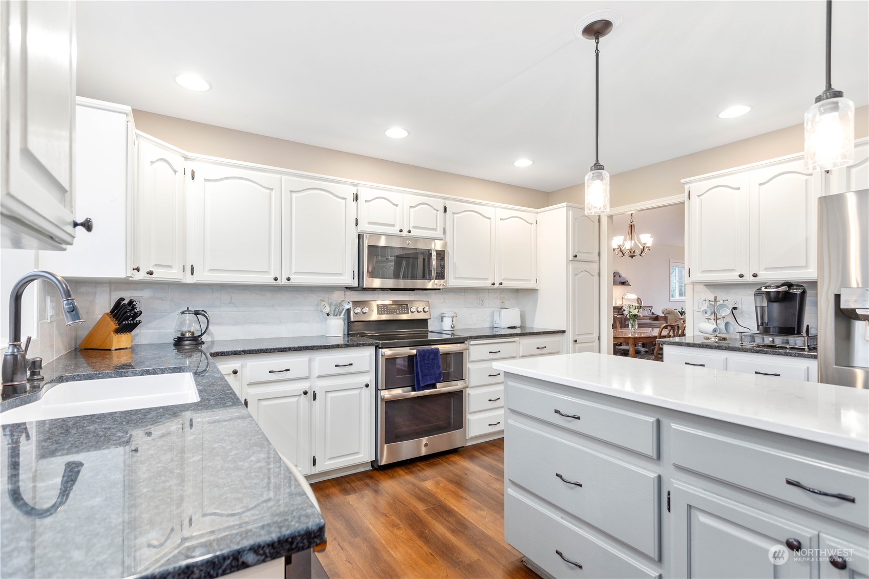 212 Springview Drive Lynden, WA 98264 - Photo 10 of 40 a kitchen with stainless steel appliances kitchen island granite countertop a stove a sink and white cabinets with wooden floor