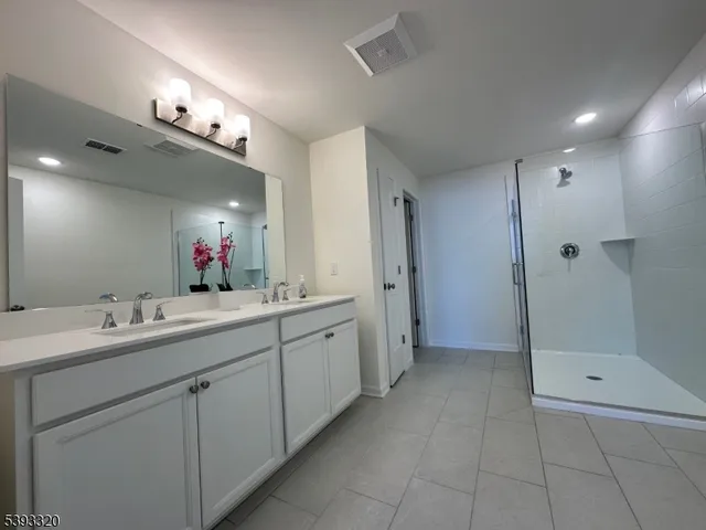 a bathroom with a double vanity sink mirror and shower
