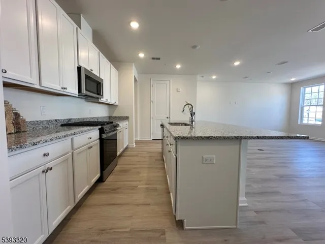a kitchen with granite countertop white cabinets and stainless steel appliances