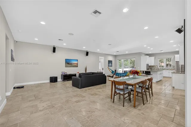 a living room with furniture a large window and kitchen view