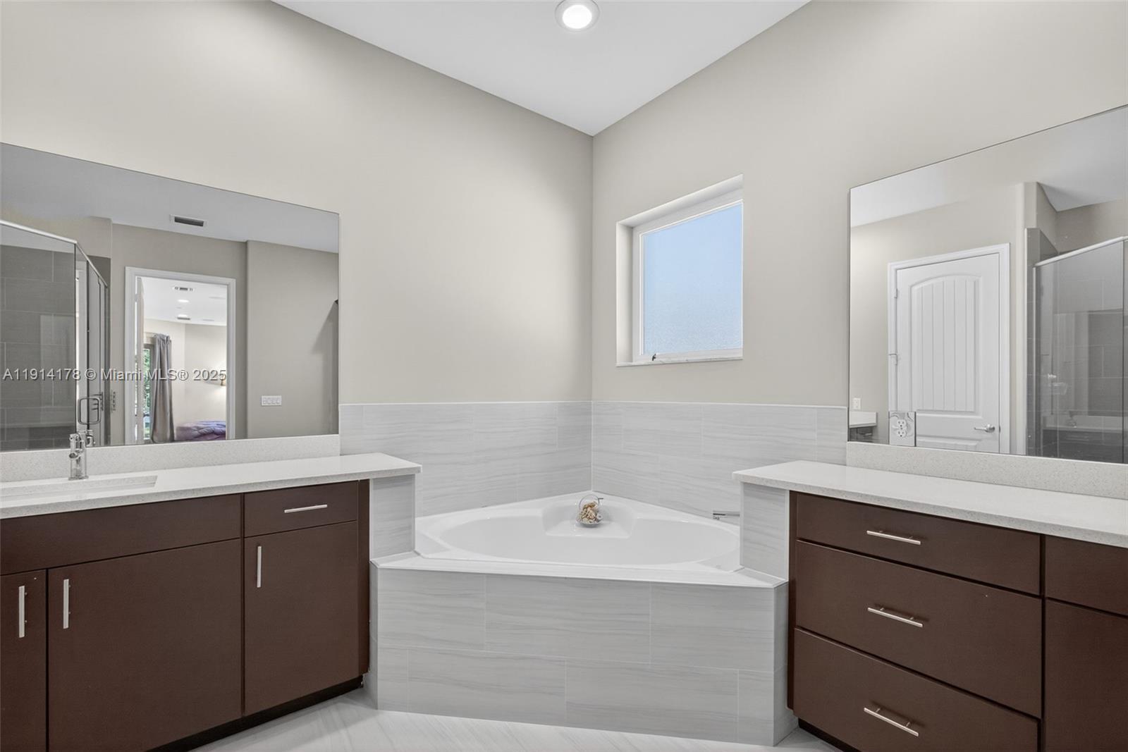 18369 Mellen Lane Jupiter, FL 33478 - Photo 31 of 84 a bathroom with a tub a sink double vanity and mirror