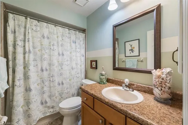 a bathroom with a granite countertop sink toilet and mirror