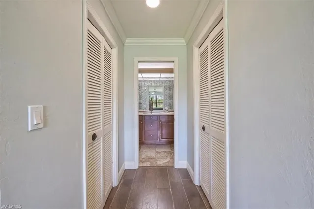 a view of a hallway with wooden floor and a bathroom