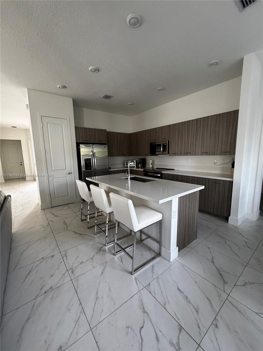 4409 Southwest 173rd Avenue Miramar, FL 33029 - Photo 11 of 38 a kitchen with stainless steel appliances a sink a stove a microwave a counter top space and cabinets
