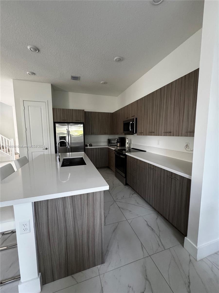 4409 Southwest 173rd Avenue Miramar, FL 33029 - Photo 12 of 38 a kitchen with a sink a stove top oven and cabinets