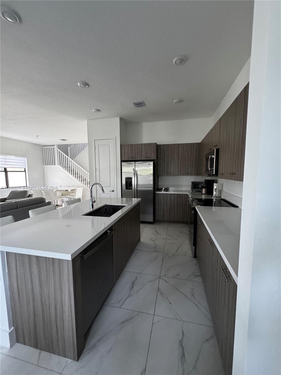 4409 Southwest 173rd Avenue Miramar, FL 33029 - Photo 13 of 38 a kitchen with stainless steel appliances a sink stove and cabinets