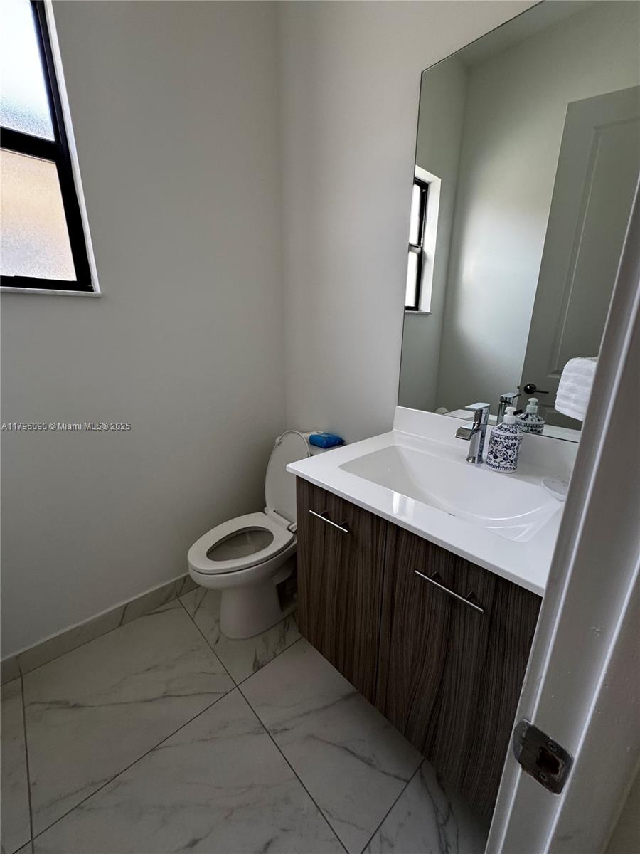 4409 Southwest 173rd Avenue Miramar, FL 33029 - Photo 6 of 38 a bathroom with a granite countertop toilet a sink and a mirror