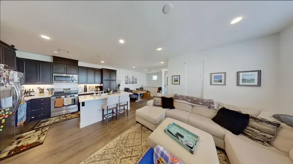 a living room with stainless steel appliances furniture and a kitchen view