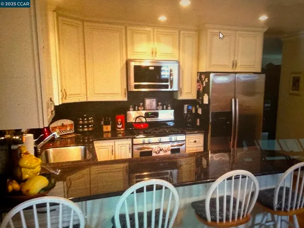 a kitchen with stainless steel appliances granite countertop a stove refrigerator and a view of living room