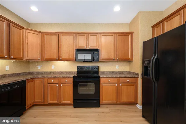 a kitchen with stainless steel appliances granite countertop wooden cabinets a sink and dishwasher with wooden floor