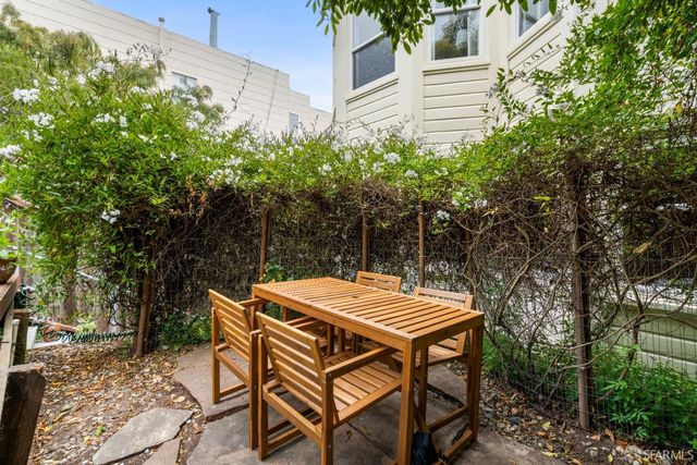 a backyard of a house with table and chairs under an umbrella