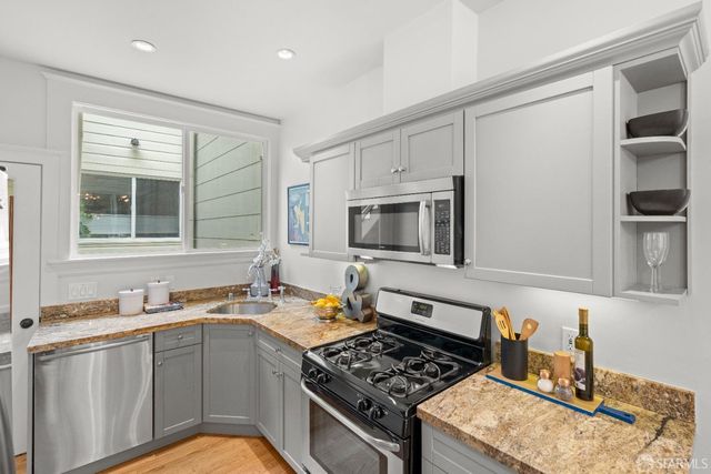 a kitchen with stainless steel appliances granite countertop a stove top oven a sink a dining table and chairs
