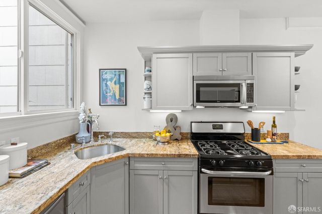 a kitchen with granite countertop a sink stove and microwave