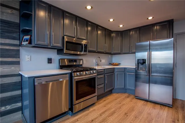 a kitchen with stainless steel appliances granite countertop a stove a refrigerator and a microwave