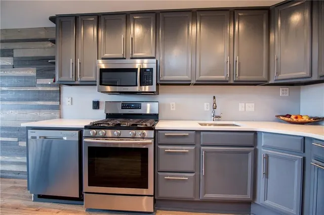 a kitchen with cabinets stainless steel appliances and wooden floor