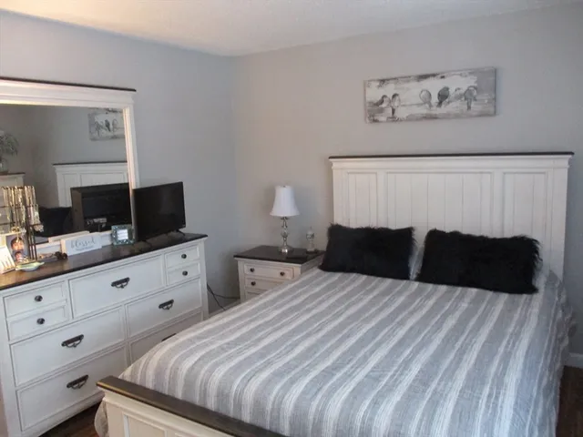 a bedroom with a bed and a flat tv screen on dresser